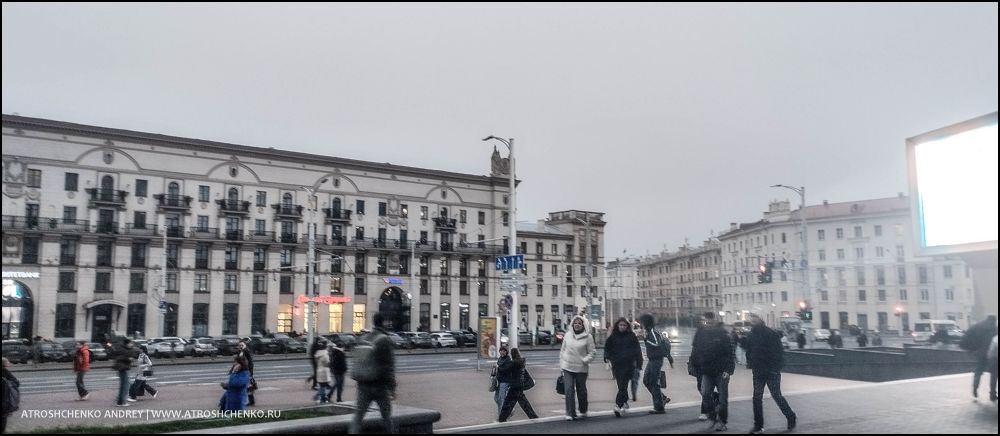 Комфортабельный автобус Ecolines на остановке в Минске на маршруте в Санкт-Петербург, вечерняя посадка пассажиров, вид на железнодорожный вокзал и архитектуру близ площади Бобруйской, начало романтического путешествия между Беларусью и культурной столицей России
