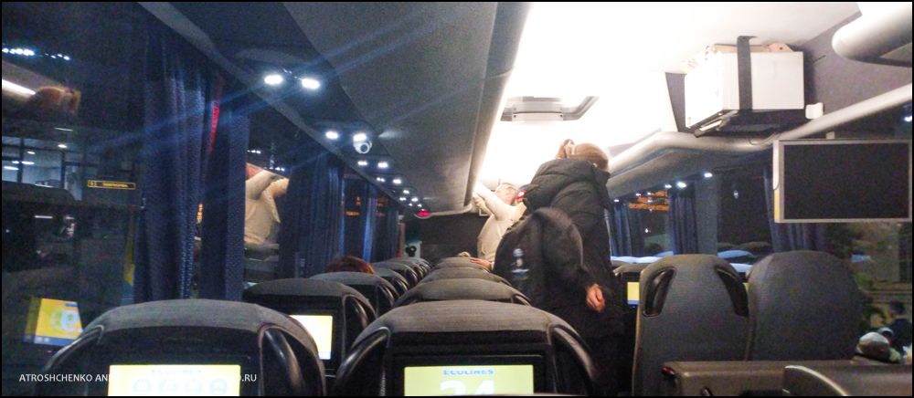 Комфортабельный автобус Ecolines на остановке в Минске на маршруте в Санкт-Петербург, вечерняя посадка пассажиров, вид на железнодорожный вокзал и архитектуру близ площади Бобруйской, начало романтического путешествия между Беларусью и культурной столицей России